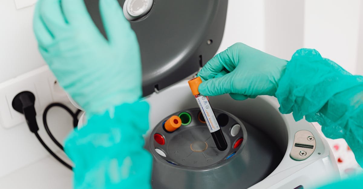 A lab technician wearing gloves uses a centrifuge for blood analysis in a modern laboratory setting.